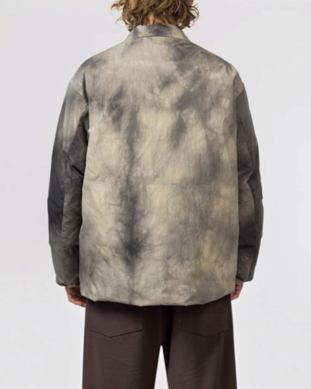 Vue arrière d'un homme portant la veste Merci Paris Snow Peak en nylon avec motif Shibori teinté couleur charbon.
