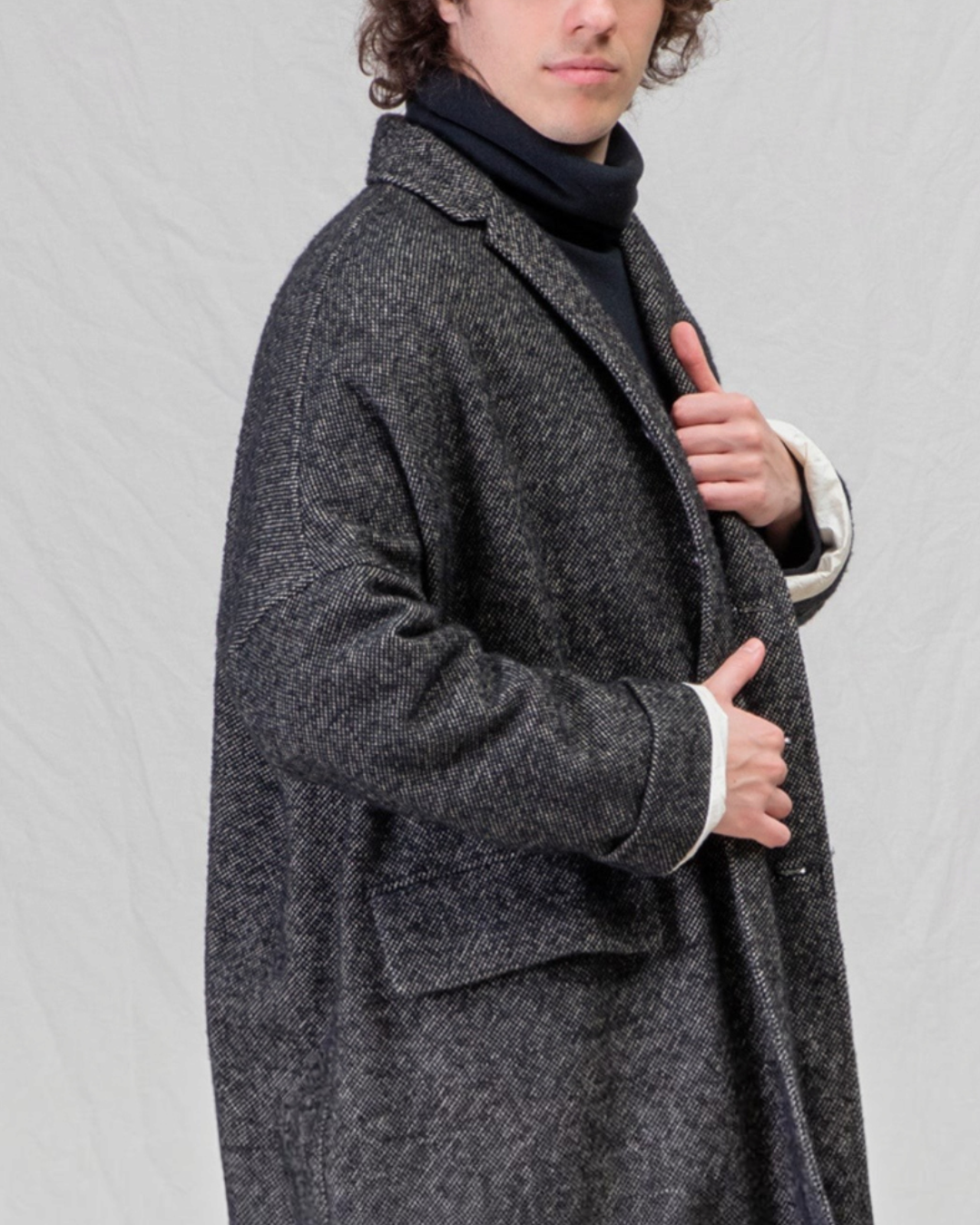 Manteau ample noir en mélange de laine Album Di Famiglia chez Merci Paris, porté par un homme aux cheveux bouclés