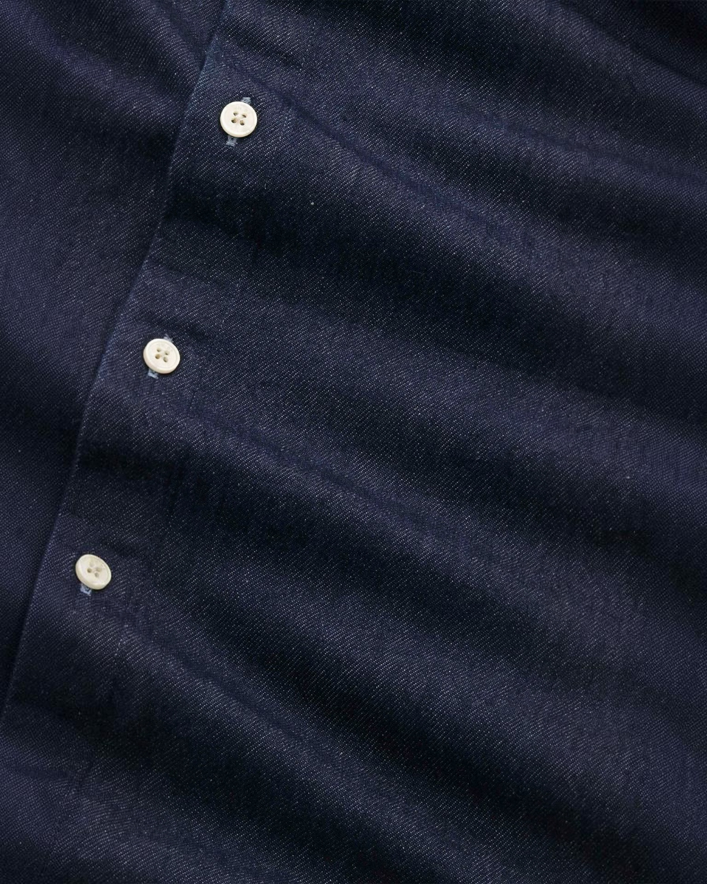 Gros plan sur la surchemise Casper Merci Paris en sergé de coton indigo avec boutons siglés et texture vintage