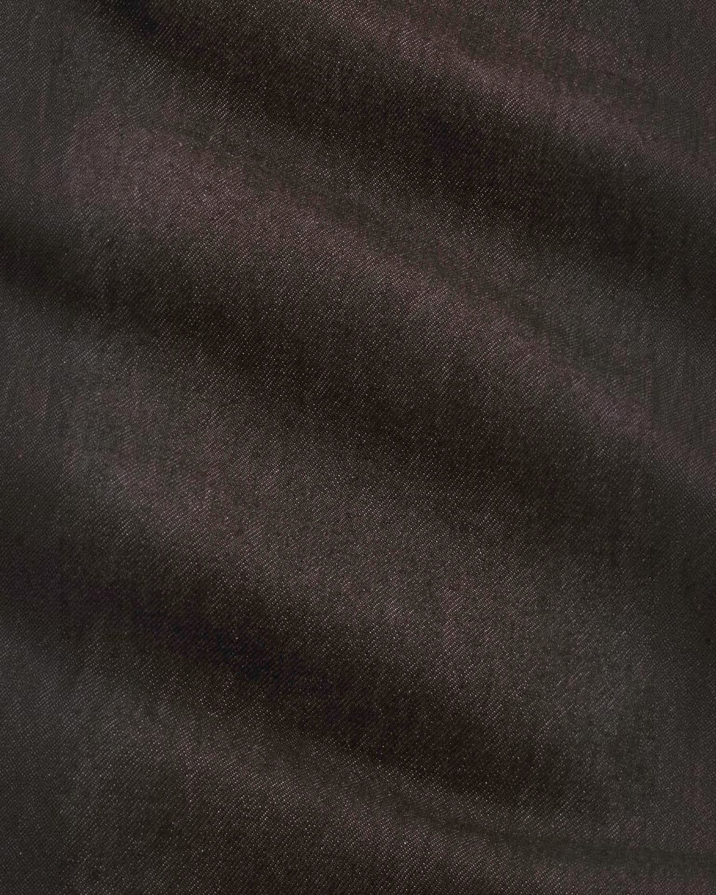Gros plan sur la texture du denim marron foncé du jean Ross de la marque Merci Paris en coton biologique et recyclé