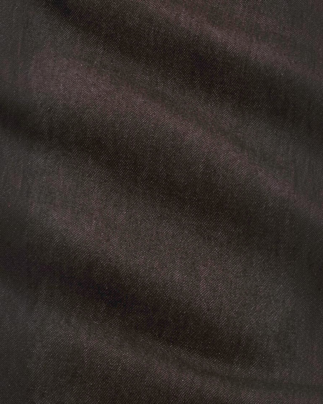 Gros plan sur la texture du denim marron foncé du jean Ross de la marque Merci Paris en coton biologique et recyclé