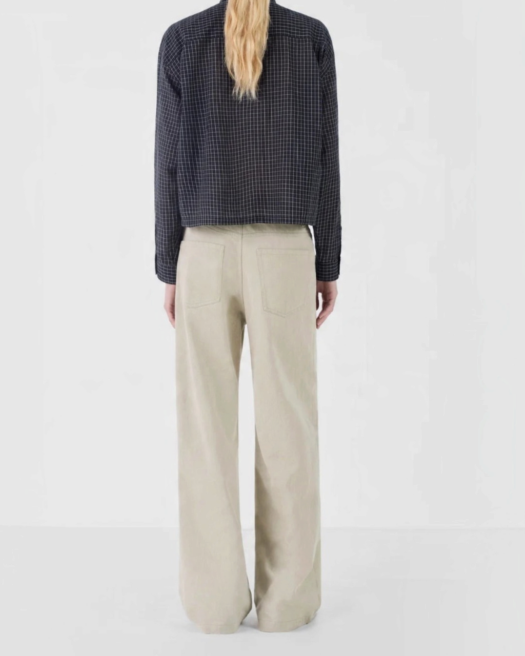 Vue arrière de la chemise courte à carreaux noirs Masscob portée avec un pantalon beige par Merci Paris