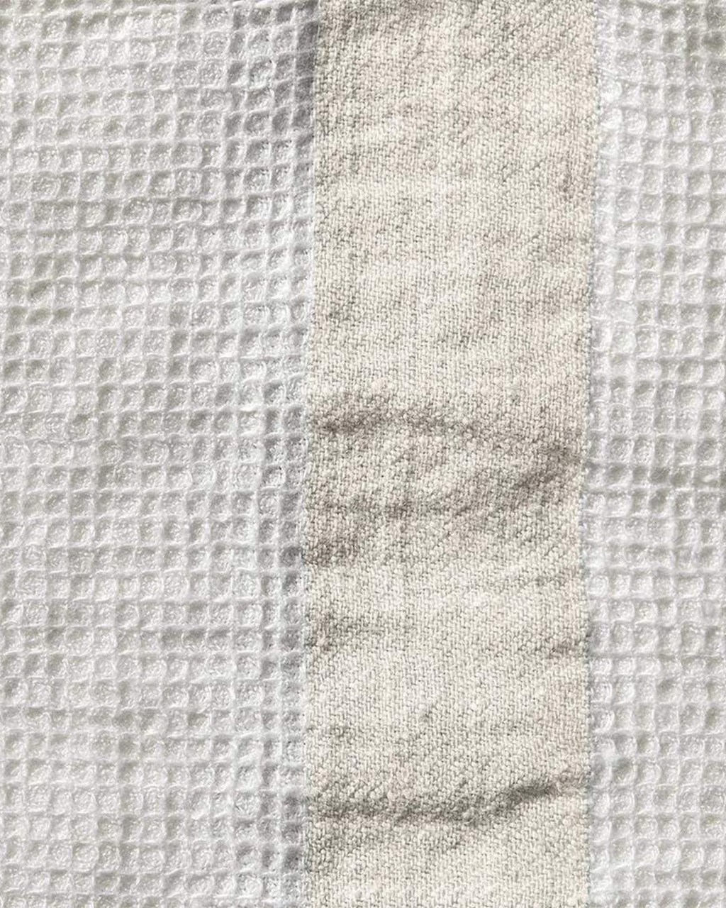 Gros plan sur le tissage nid d'abeille d'une serviette de bain en lin Merci Paris couleur pierre