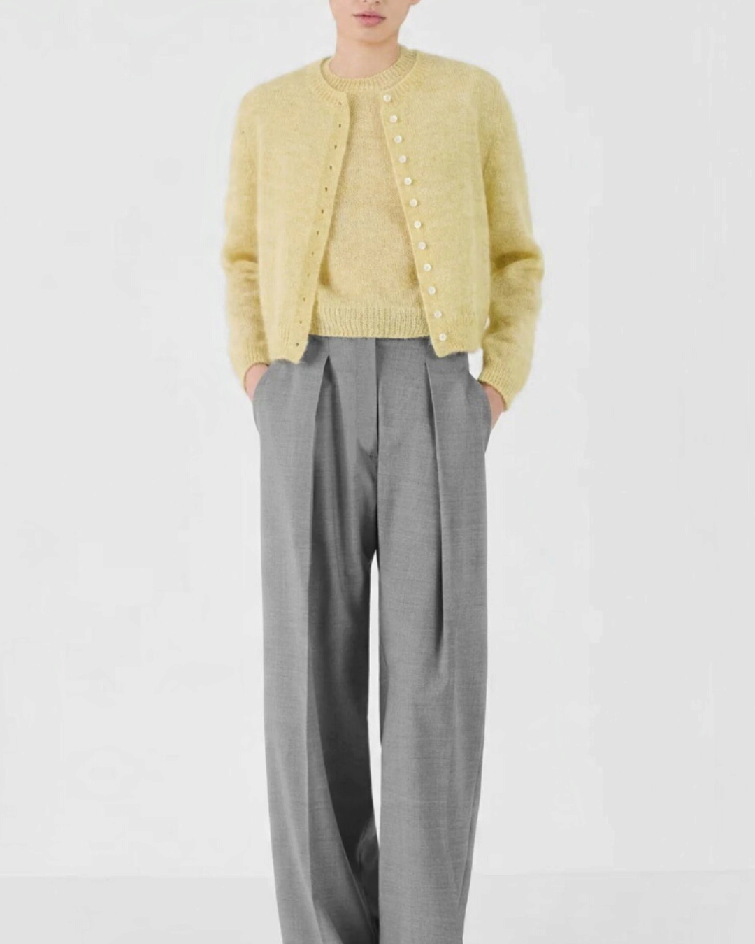 Mannequin portant le cardigan court Merci Paris Masscob en mohair jaune citron avec un pantalon gris large