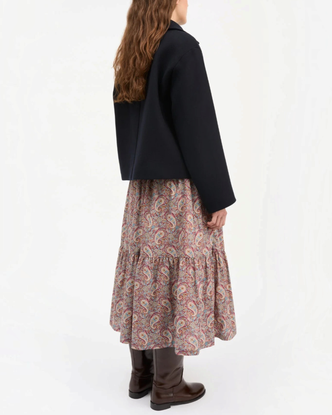 Short navy jacket Skall Studio in recycled wool worn by a woman with a long patterned skirt