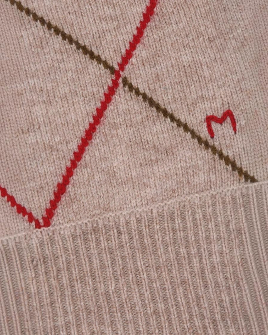 Gros plan sur le gilet Auguste Merci Paris en laine mérinos beige avec motif argyle rouge et broderie M