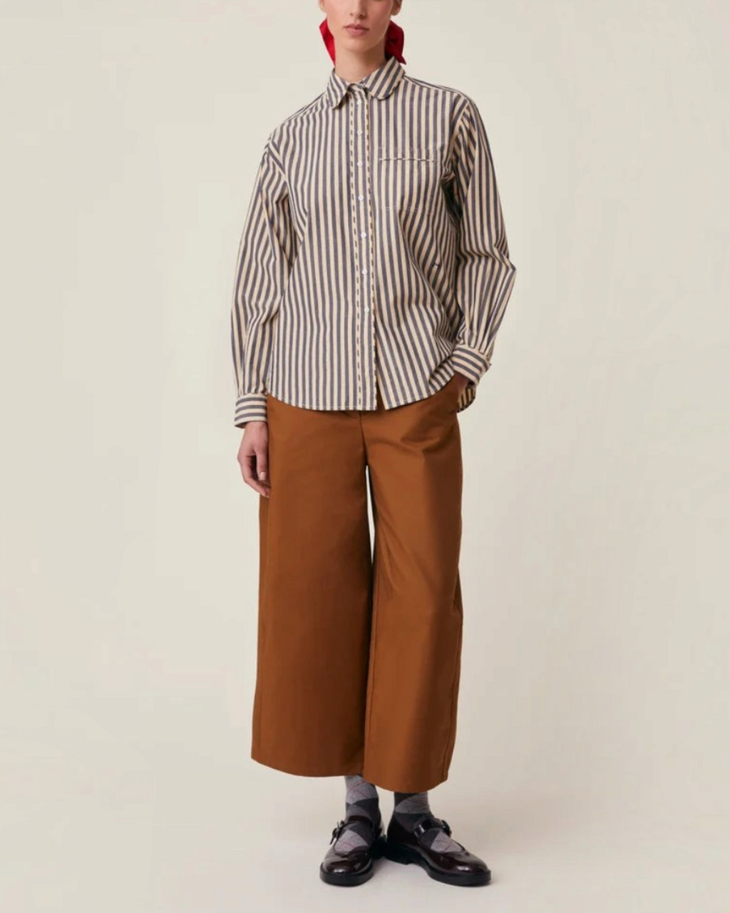 Modèle portant la chemise Henriette Merci Paris en coton rayé bleu et beige avec col rond et poche poitrine