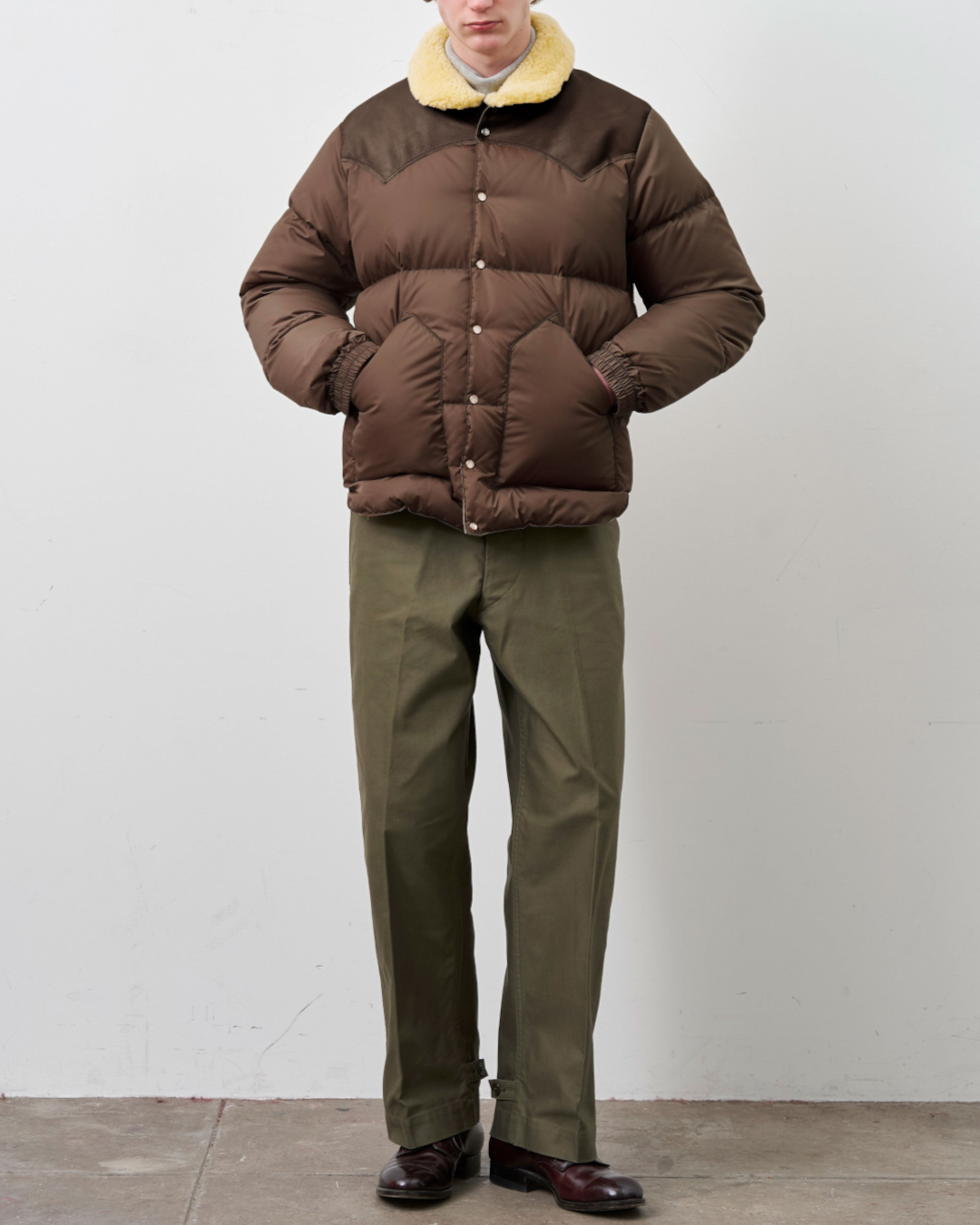 Homme portant une doudoune Merci Paris Rocky Mountain marron foncé avec empiècement en cuir et col en peau lainée