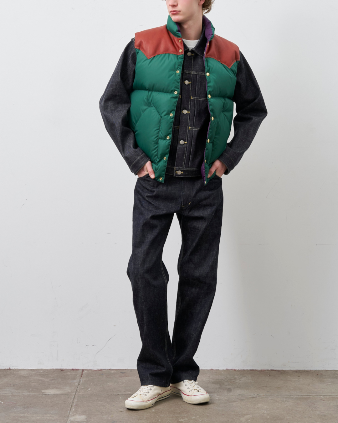 Homme portant un gilet en duvet Merci Paris Rocky Mountain vert et marron avec empiècement en cuir sur une veste denim