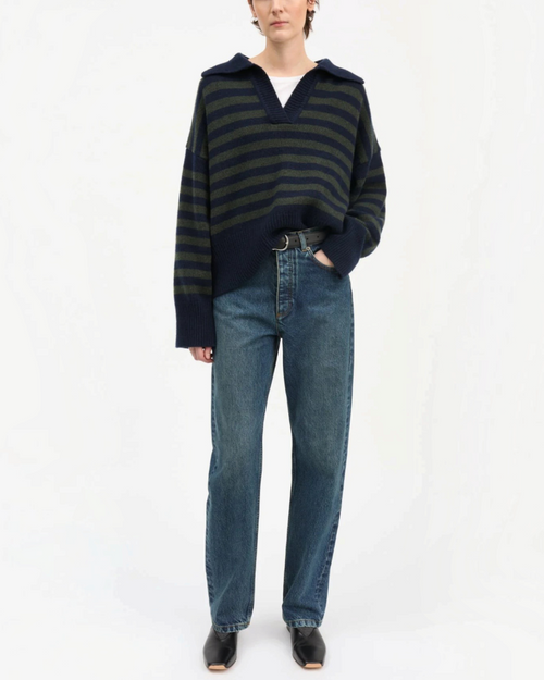 Pull Skall Studio en laine mérinos rayé marine et vert à col V porté par une femme avec un jean bleu