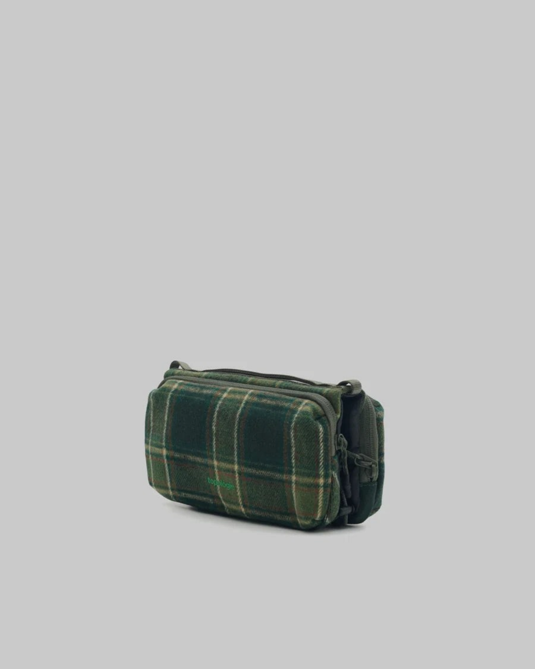 Sac bandoulière Merci Paris Topologie Bottle Sacoche Medium en tissu vert à motif tartan avec compartiments zippés.