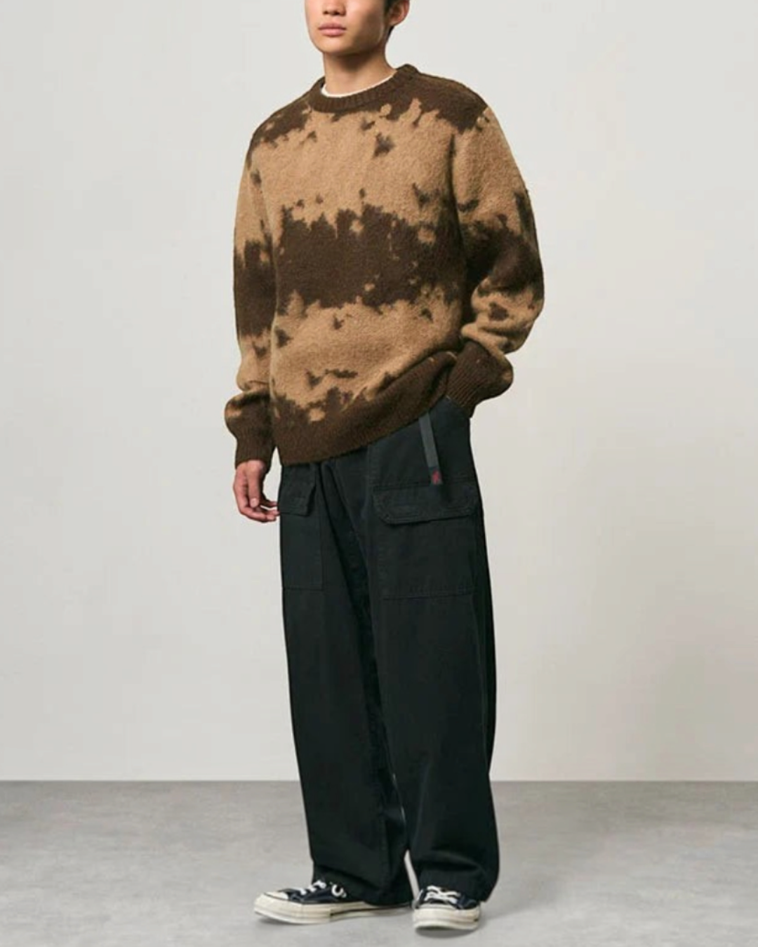 Homme portant un pull Gramicci en maille mohair taupe à motif éclaboussures marron foncé avec un pantalon noir