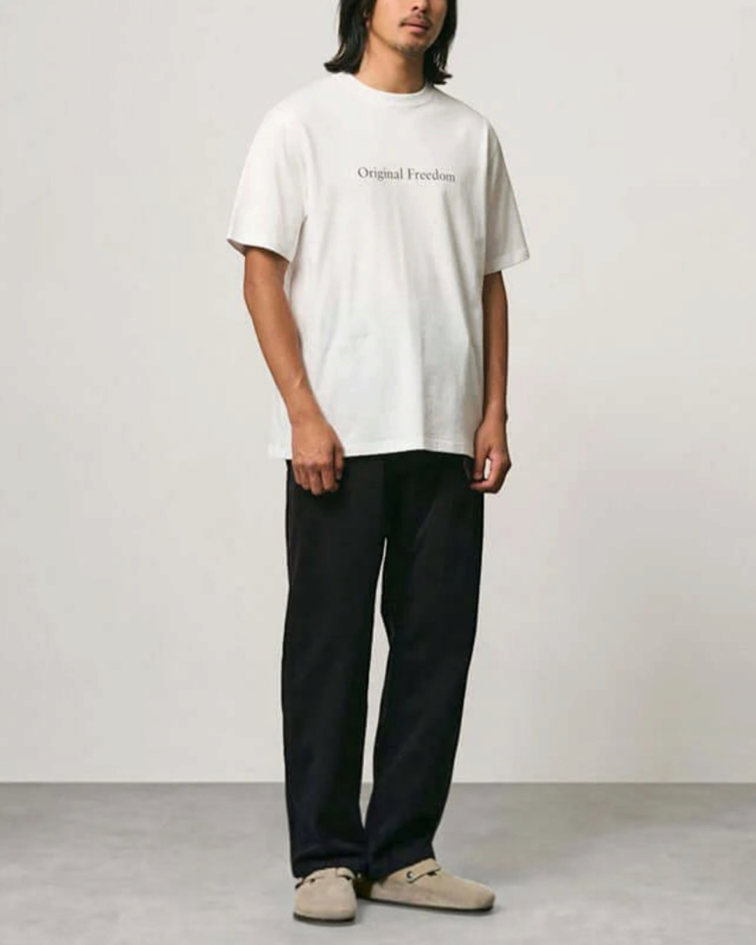 Homme portant un t-shirt blanc en coton Merci Paris Gramicci avec inscription Original Freedom et col rond