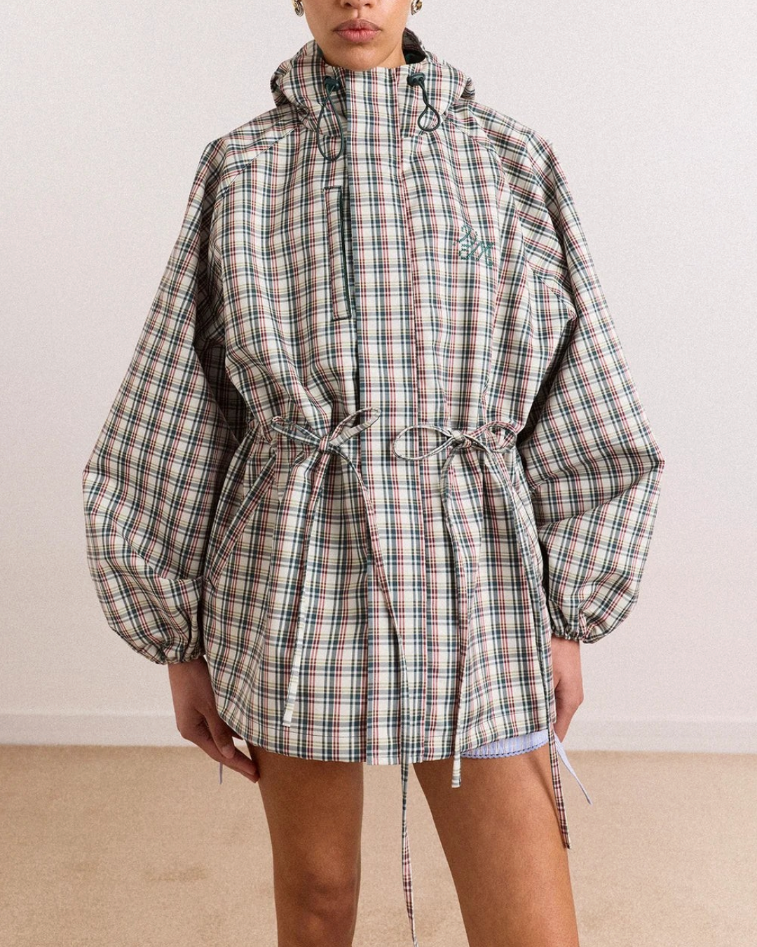 Modèle portant l'imperméable Merci Paris Damson Madder à carreaux multicolores, coupe ample et taille ajustable.