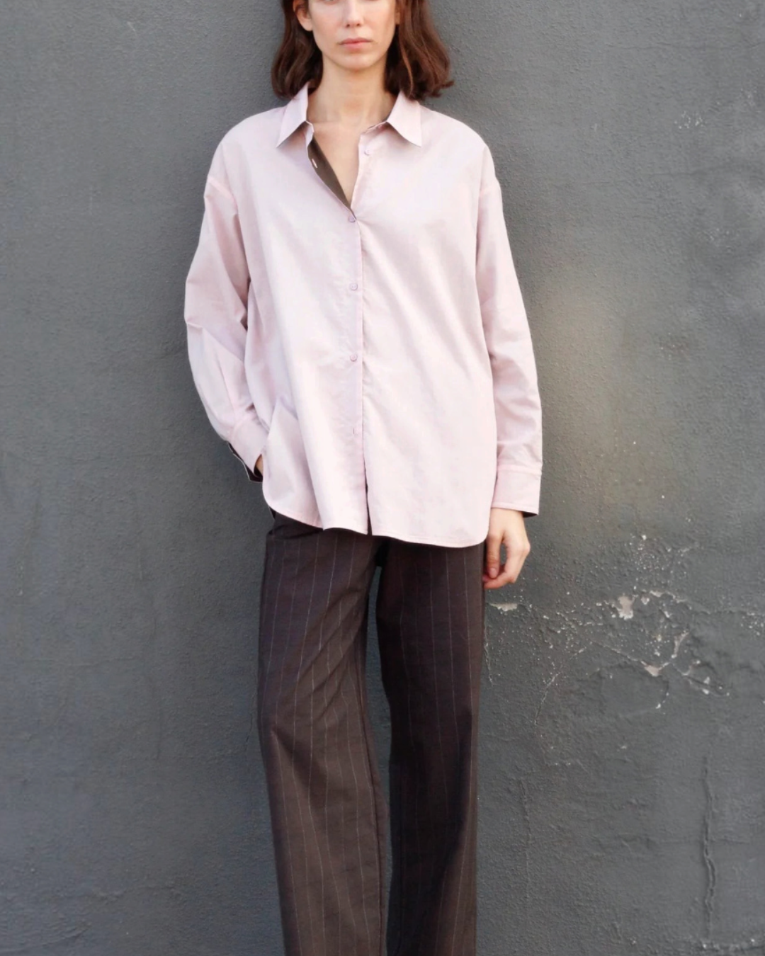 Mannequin portant la chemise réversible Merci Paris en coton biologique rose oversize avec col et revers marron