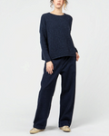 Modèle portant un pantalon denim bleu indigo Merci Paris à coupe ample avec taille élastiquée et pull assorti