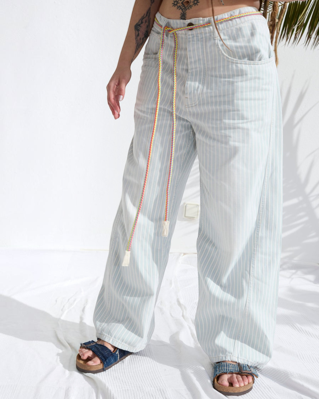 Pantalon P84 Dungaree Merci Paris en coton rayé bleu et écru, coupe large avec ceinture en corde artisanale