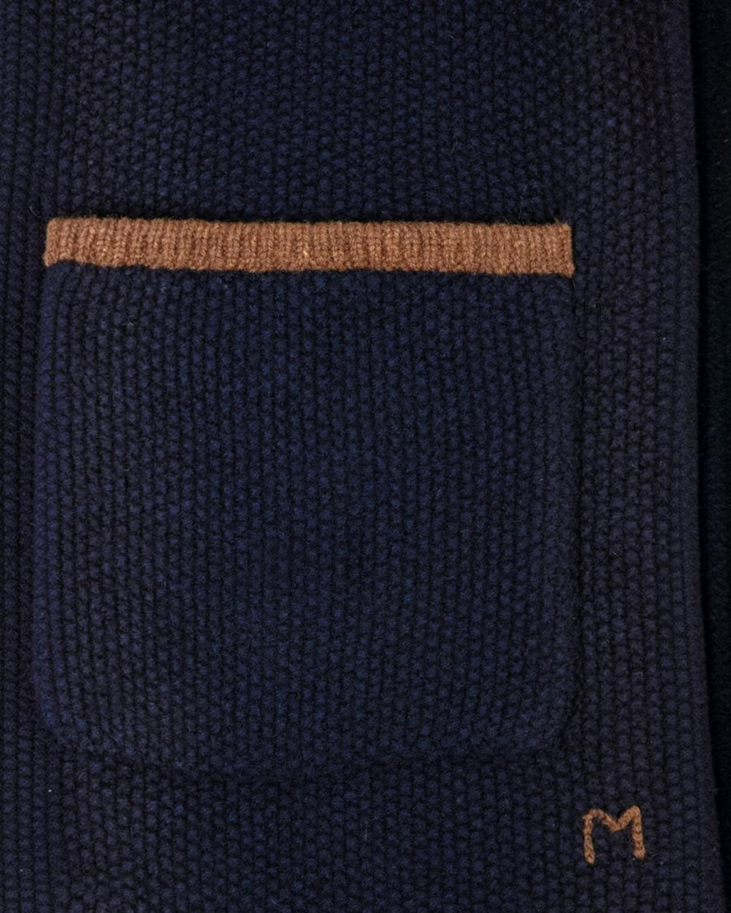 Gros plan sur la poche plaquée du gilet Angele Merci Paris en laine mérinos bleu marine avec bordure contrastée camel