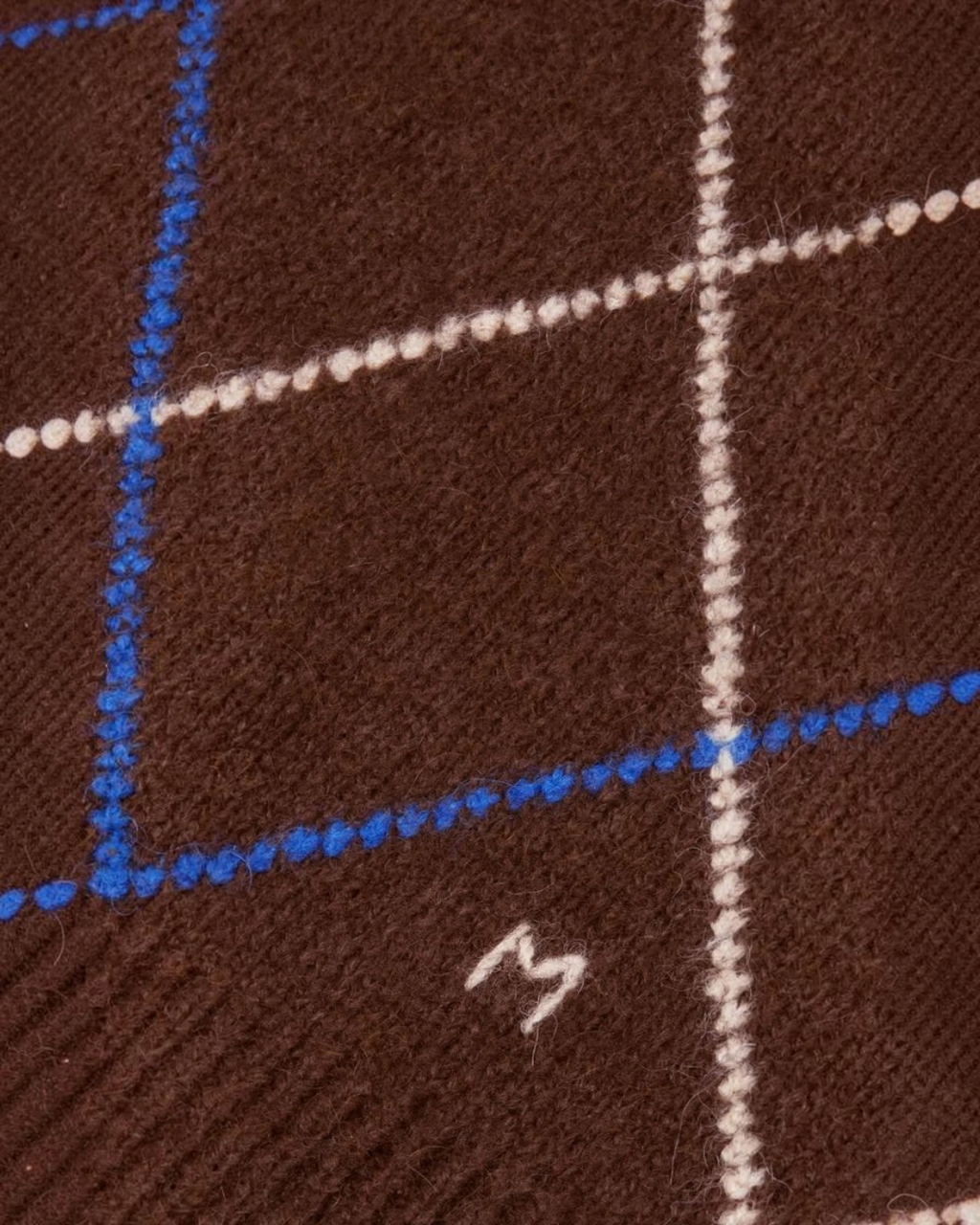 Gros plan sur la maille douce en alpaga du pull Merci Paris Moismont Eddy avec motif arlequin marron, bleu et blanc