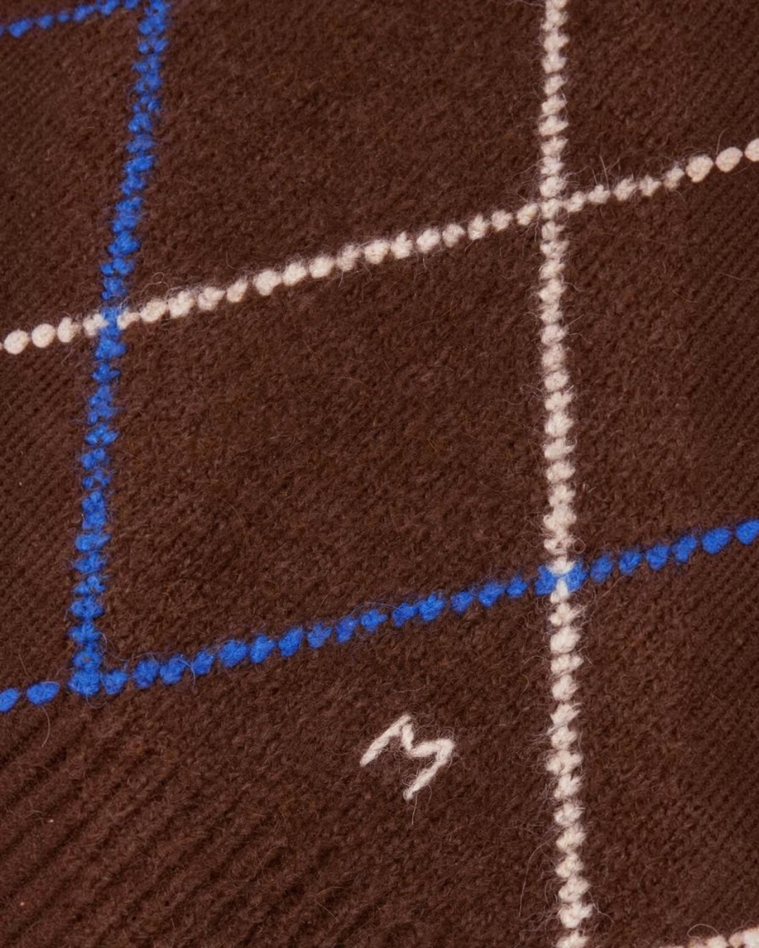 Gros plan sur la maille douce en alpaga du pull Merci Paris Moismont Eddy avec motif arlequin marron, bleu et blanc