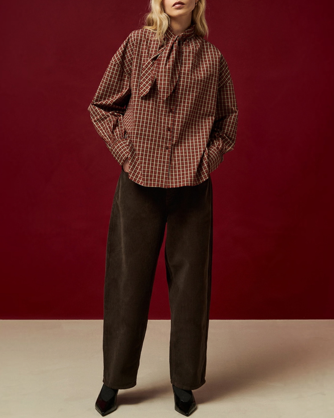Modèle portant la blouse Merci Paris Belle Pièce Tom en coton à carreaux couleur spice avec col à nouer