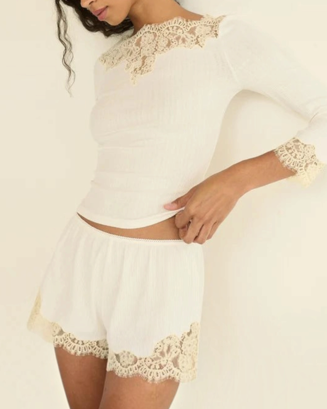 Model wearing the white Riana T-shirt by Merci Paris in ribbed knit with lace at the neckline and sleeves