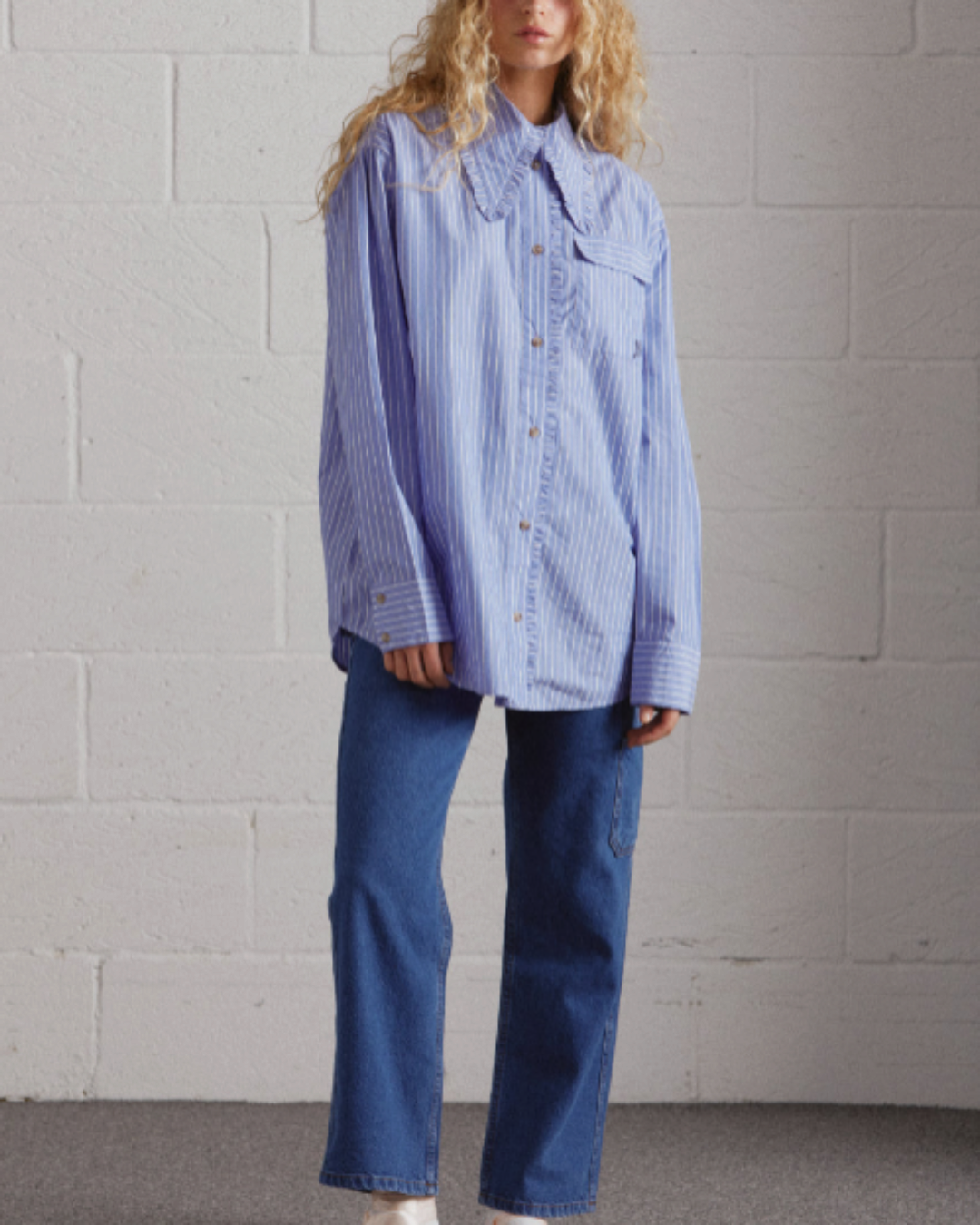 Chemise Damson Madder à rayures bleues et blanches avec col à volants brodé, portée avec un jean bleu