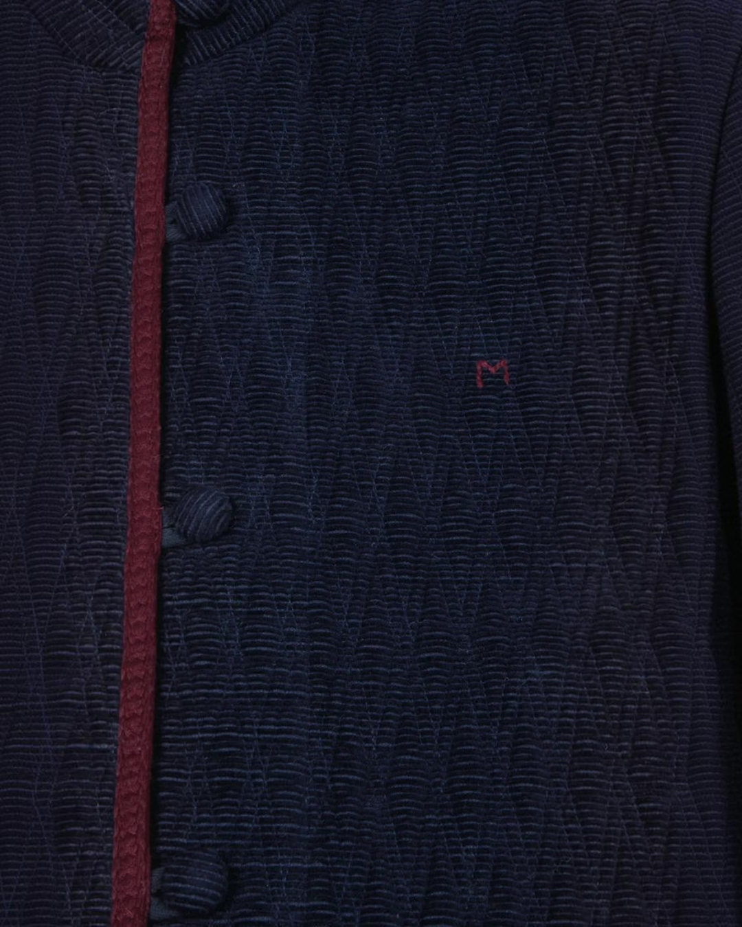 Gros plan sur la veste Marianne Merci Paris en velours de coton bleu marine avec passepoil contrastant bordeaux
