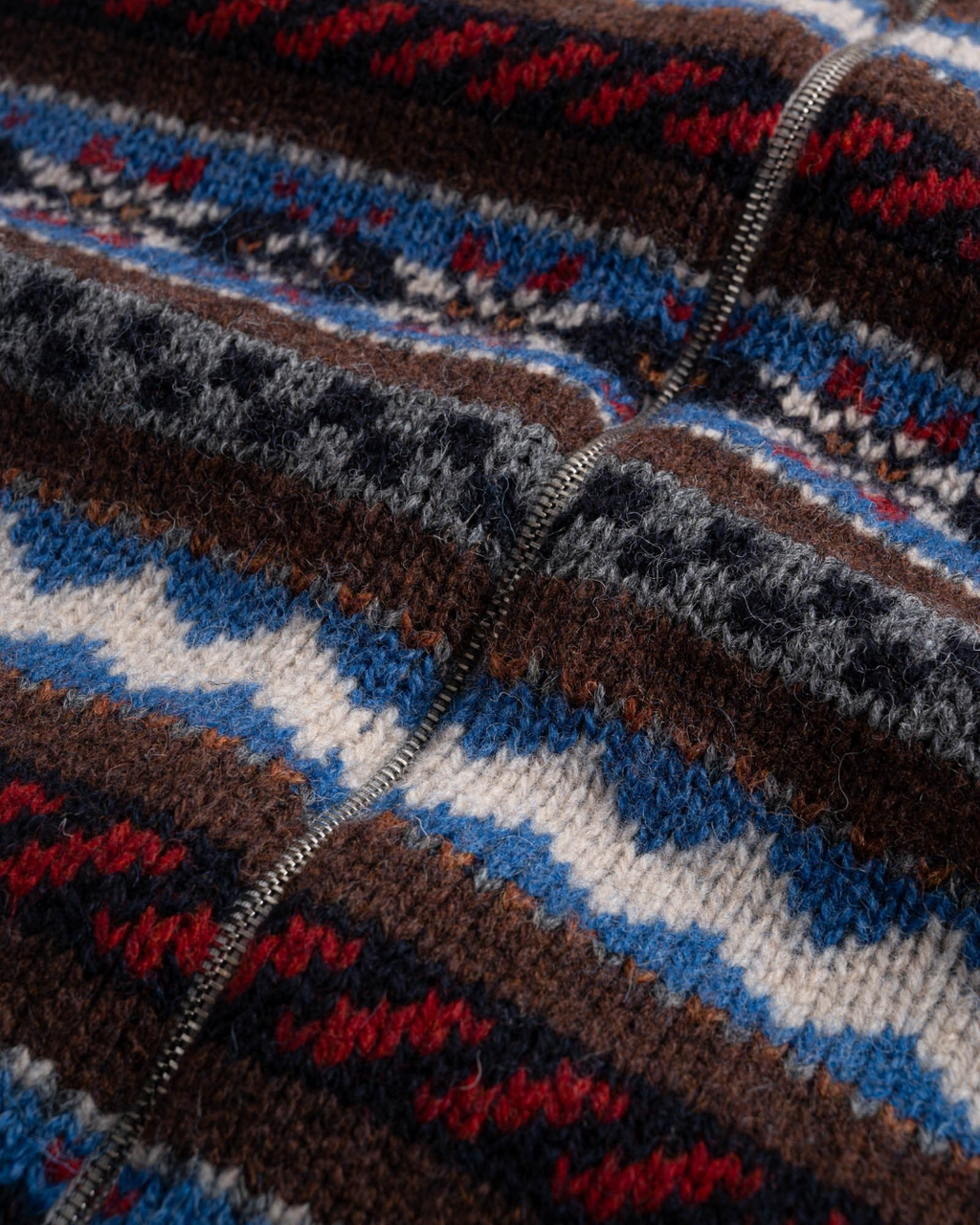 Gros plan sur le cardigan zippé Merci Paris Howlin' en laine vierge avec motifs Fair Isle colorés et géométriques