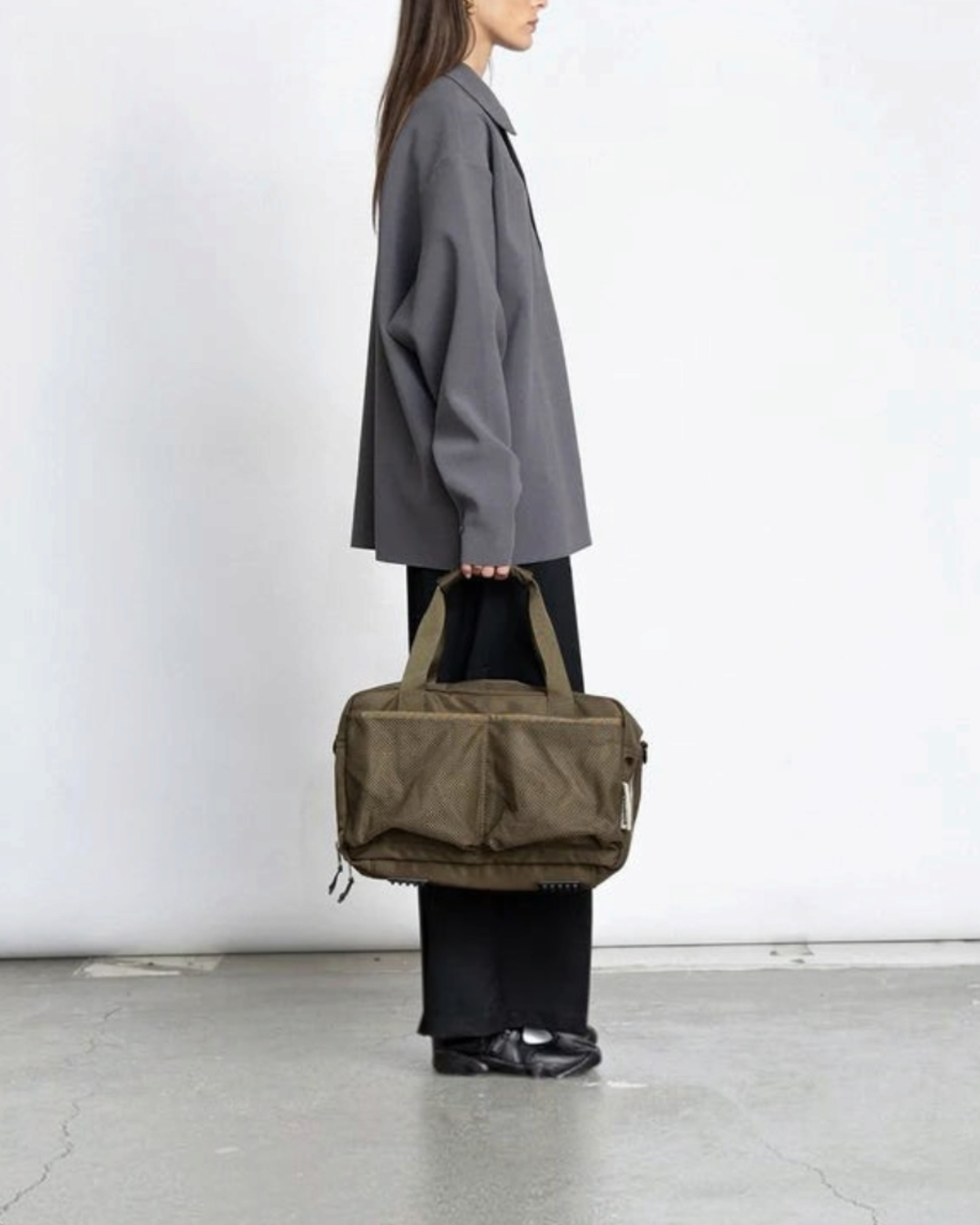 Modèle portant le sac weekend 18L kaki de Merci Paris en nylon recyclé avec poches en filet, vue de profil