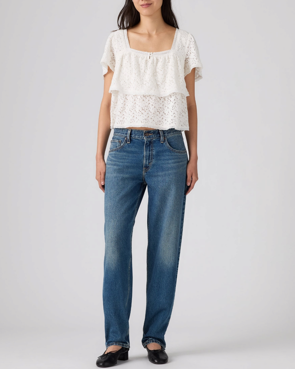 Modèle portant un jean Levi's Loose Taper bleu en coton avec un haut blanc en dentelle chez Merci Paris
