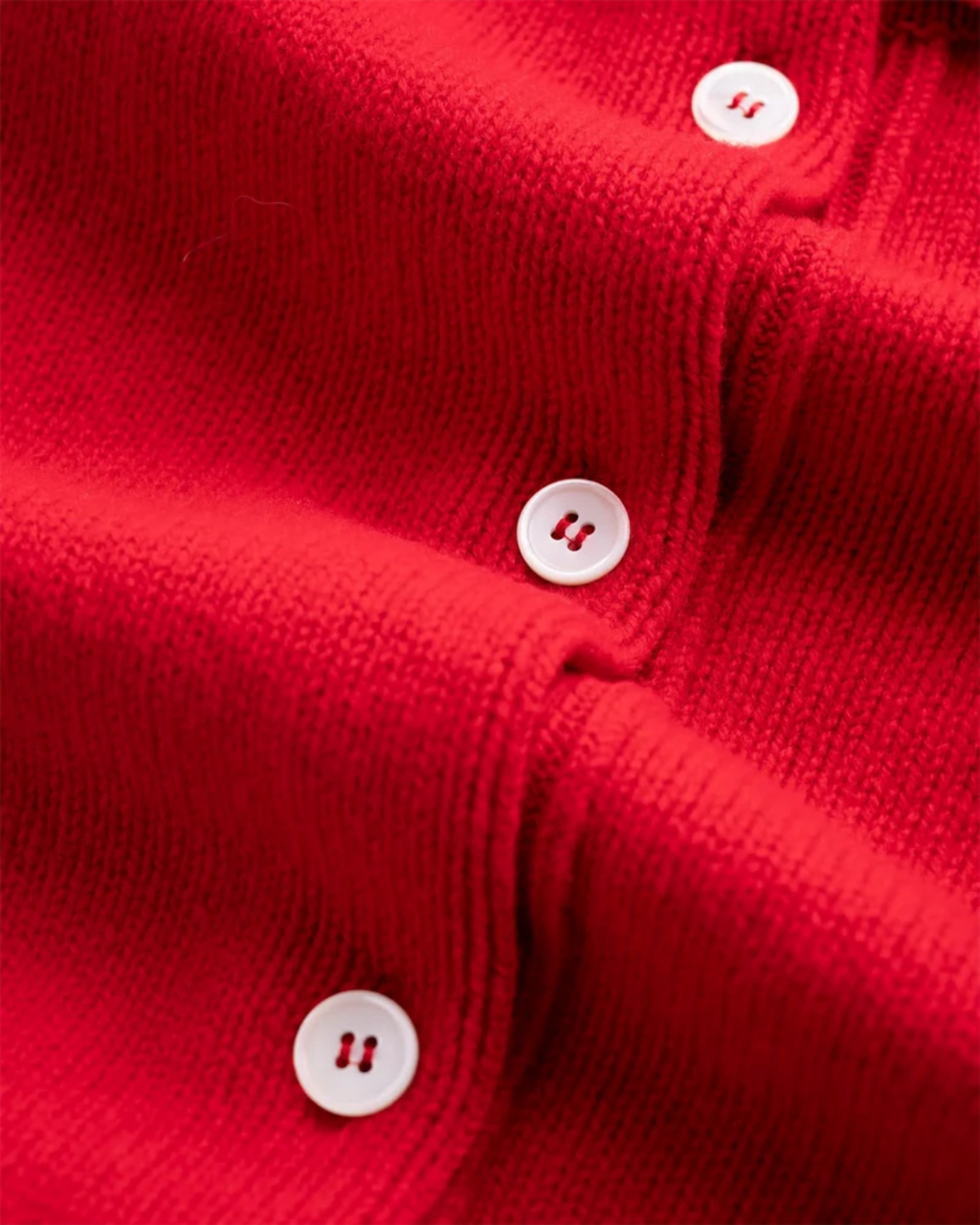 Gros plan sur le cardigan rouge Merci Paris Howlin' en laine d'agneau avec boutons en nacre contrastants